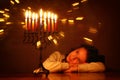 Low key image of jewish holiday Hanukkah background with cute girl looking at menorah & x28;traditional candelabra& x29; Royalty Free Stock Photo