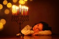 Low key image of jewish holiday Hanukkah background with cute girl looking at menorah & x28;traditional candelabra& x29; Royalty Free Stock Photo