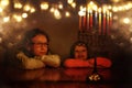 Low key image of jewish holiday Hanukkah background with two cute kids looking at menorah & x28;traditional candelabra& x29; Royalty Free Stock Photo