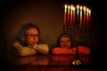 Low key image of jewish holiday Hanukkah background with two cute kids looking at menorah & x28;traditional candelabra& x29; Royalty Free Stock Photo
