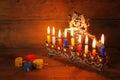 Low key image of jewish holiday Hanukkah with menorah (traditional Candelabra), donuts and wooden dreidels (spinning top) Royalty Free Stock Photo