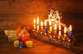 Low key image of jewish holiday Hanukkah with menorah (traditional Candelabra), donuts and wooden dreidels (spinning top) Royalty Free Stock Photo