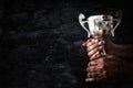 low key image of a man holding a trophy cup over dark background. Royalty Free Stock Photo