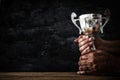 low key image of a man holding a trophy cup over dark background. Royalty Free Stock Photo