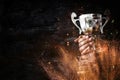 low key image of a man holding a trophy cup over dark background Royalty Free Stock Photo