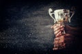 low key image of a man holding a trophy cup over dark background Royalty Free Stock Photo