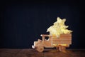 Low key image of retro wooden toy car with garland golden stars over wooden table. nostalgia and simplicity concept Royalty Free Stock Photo