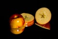 Low key image of A single sliced golden and red apple on a reflective surface on a black background with room for copy. Royalty Free Stock Photo