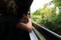 Low key image tone. Wide angle shot of young Asian tourist looking nature view from windows of the train. Royalty Free Stock Photo