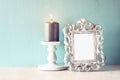 Low key image of vintage antique classical frame and Burning candle on wooden table. filtered image Royalty Free Stock Photo