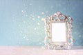 Low key image of vintage antique classical frame and wooden table and glitter lights background. filtered image