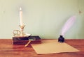 Low key image of white Feather, inkwell, burning Candle and ancient book on wooden table. filtered image. Royalty Free Stock Photo