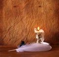 Low key image of white Feather, inkwell and burning candle on a wooden table. Royalty Free Stock Photo