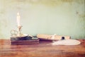 Low key image of white Feather, inkwell and candle on old wooden table. image textured