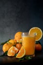 glass of fresh orange juice next to a set of oranges and tangerines Royalty Free Stock Photo