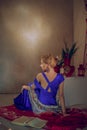 Beautiful girl in long evening dress on the floor near bureau reding book