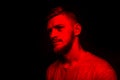 Low key portrait of bearded young man in red light on black backdrop Royalty Free Stock Photo