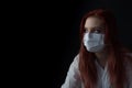 Low key portrait of redhead young woman with a medical face mask Royalty Free Stock Photo