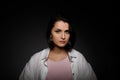 Low key portrait of serious young brunette multiethnic woman in pink tank and white shirt looking at camera Royalty Free Stock Photo