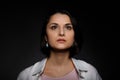 Low key portrait of serious young brunette multiethnic woman in pink tank and white shirt looking up Royalty Free Stock Photo