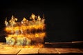 low key of queen/king crown burning over old books. vintage filtered. fantasy medieval period.