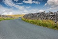 Low level view of a rural asphalt road, appearing deserted ascending a mountain in the Yorkshire Dales. Royalty Free Stock Photo