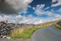 Low level view of a rural asphalt road, appearing deserted ascending a mountain in the Yorkshire Dales. Royalty Free Stock Photo