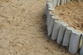 Low palisade of logs in a sandbox bordering a play area on a playground from a path in the sand Royalty Free Stock Photo