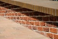 Low parapet made of red and dark red bricks beside brick pavement