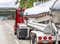 Low profile pro red big rig semi truck transporting cargo in tank semi trailer running on the road with truss bridge Royalty Free Stock Photo