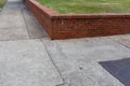 Low red brick retaining wall separating a grassy area from sidewalks, corner view at an intersection