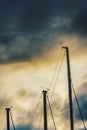 Low rise evening view of moored yachts masts and sails, against stormy weather with dense clouds