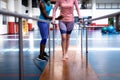 Female physiotherapist helping disabled senior woman walk with parallel bars in sports center Royalty Free Stock Photo