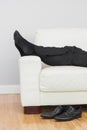 Low section of businessman resting on sofa in living room Royalty Free Stock Photo