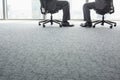 Low section of businessmen sitting on office chairs