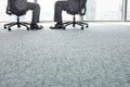 Low section of businessmen sitting on office chairs