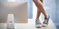 Composite image of low section of businesswoman standing on table by computer