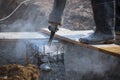 Low section of construction worker using jackhammer drill to breaking reinforced concrete pillar in construction site