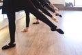 Low section of The graceful legs of ballet dancers standing in a row perform stretching exercises