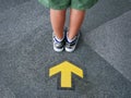 Low Section of Kid Standing In Front Of Yellow Directional Arrow Royalty Free Stock Photo
