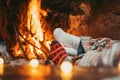 Low section legs of husband and wife covered in socks and warm blanket relaxing in front of burning fireplace during winter Royalty Free Stock Photo