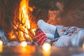 Low section legs of husband and wife covered in socks and warm blanket relaxing in front of burning fireplace during winter