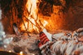 Low section legs of husband and wife covered in socks and warm blanket relaxing in front of burning fireplace during winter