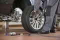 Low section of male mechanic repairing car's tire in repair shop