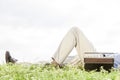 Low section of man lying by vintage radio on grass against clear sky