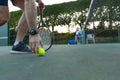 Low section of man holding tennis racket picking up ball on outdoor tennis court, with copy space Royalty Free Stock Photo