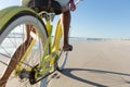 Low section of mixed race woman on beach holiday riding bicycle on the sand by the sea