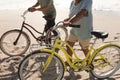 Low section of multiracial senior couple walking with bicycles on sand at beach during sunny day Royalty Free Stock Photo