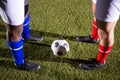 Low section of players standing by soccer ball