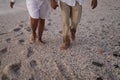 Low section of senior multiracial couple holding hands walking barefoot on sand at beach Royalty Free Stock Photo